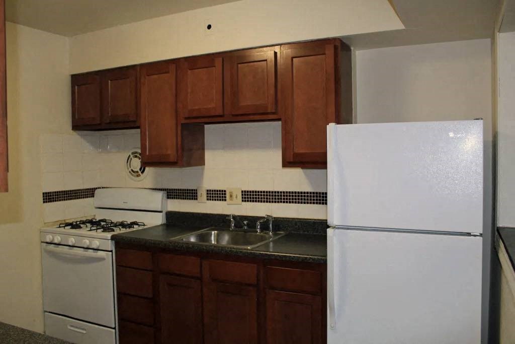 a kitchen with a white refrigerator freezer next to a stove top oven