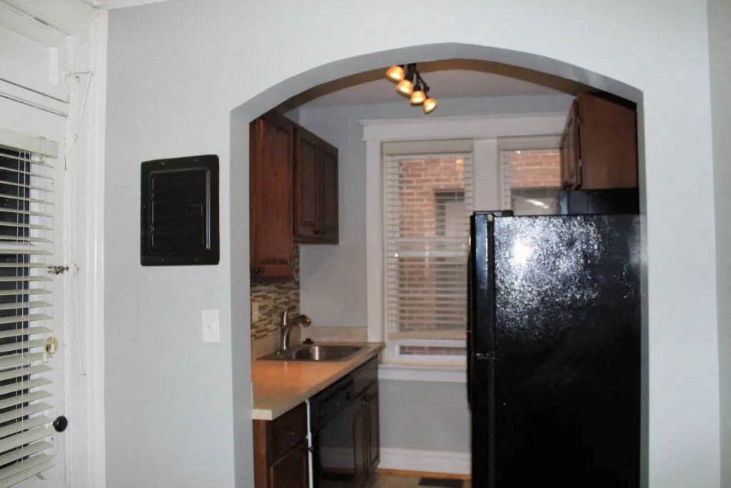a kitchen with a black refrigerator freezer next to a window