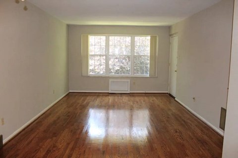 a large empty room with a window and a radiator