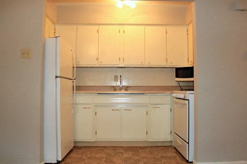 a kitchen with a white refrigerator freezer next to a stove top oven