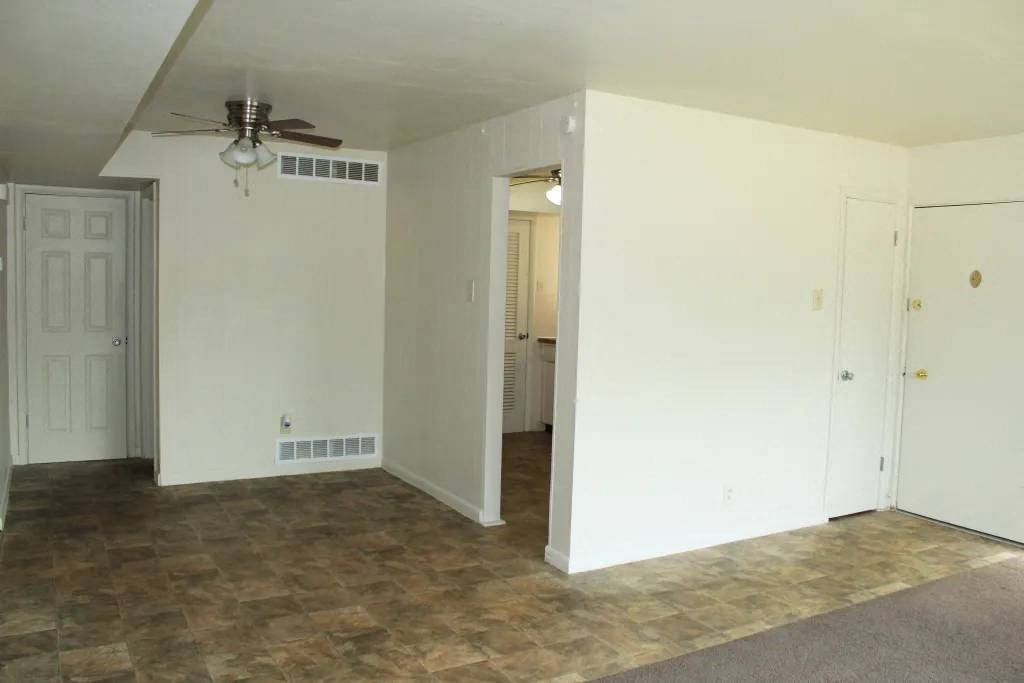 a living room with a ceiling fan and white walls