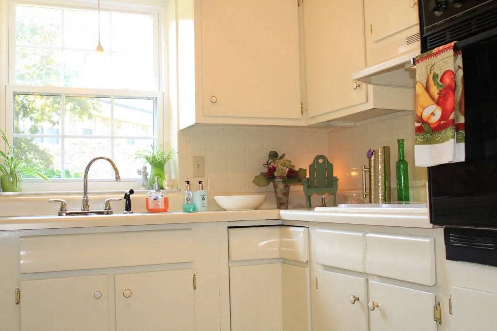 a kitchen with white cabinets and a window
