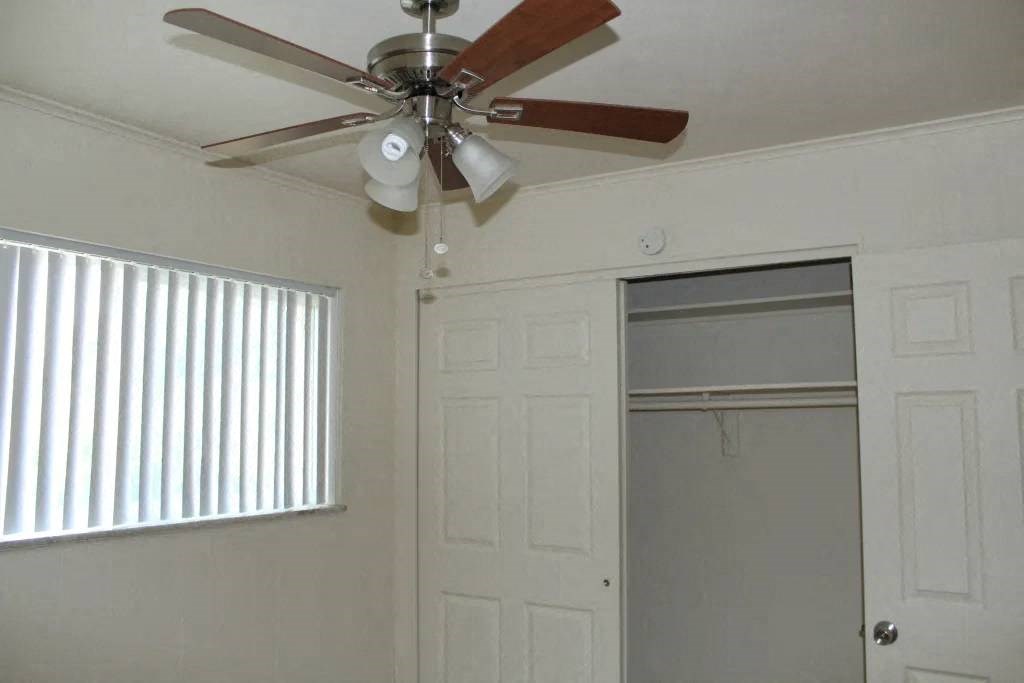 a ceiling fan hangs in a bedroom next to a closet