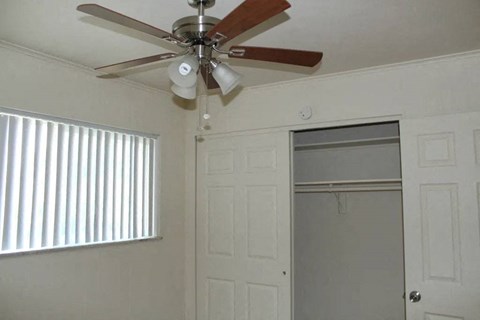 a ceiling fan hangs in a bedroom next to a closet