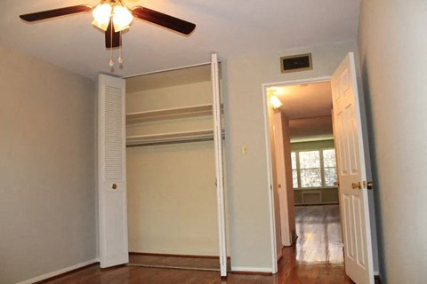 a bedroom with a ceiling fan and a closet with a door open