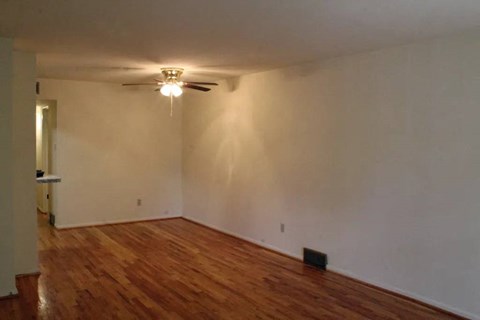 an empty room with a ceiling fan and hardwood floors