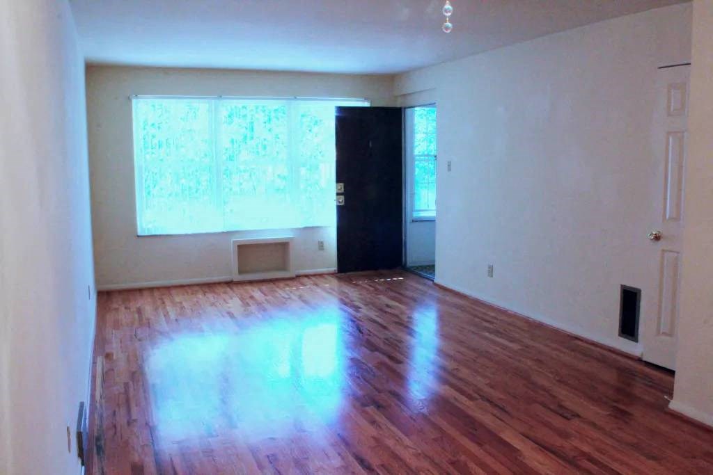 an empty room with a door and two windows