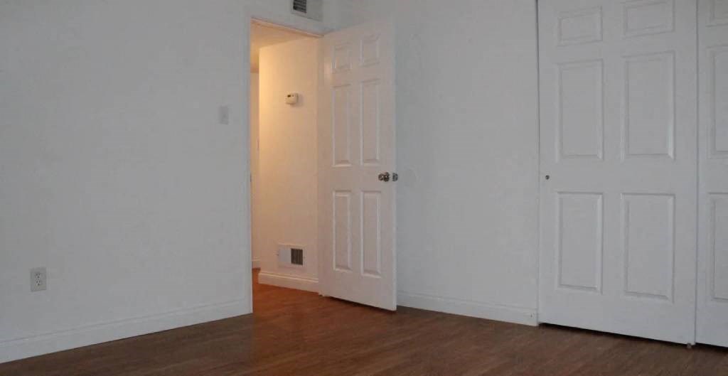 a bedroom with two white doors and a wooden floor