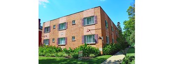 a red brick apartment building with purple shutters