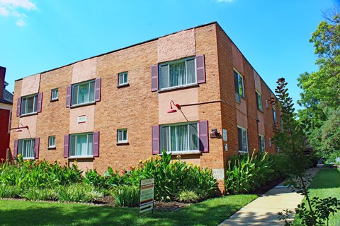 a red brick apartment building with purple shutters