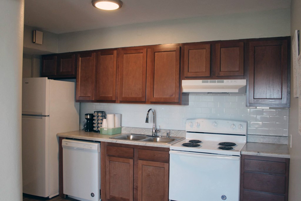 an empty kitchen with white appliances and wooden cabinets
