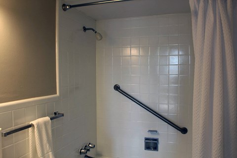 a bathroom with a shower with white tiles and a towel rack