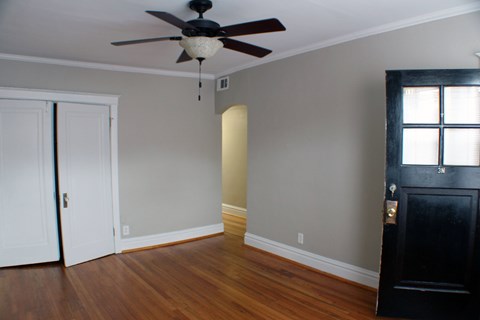 A room with a ceiling fan and a black door.