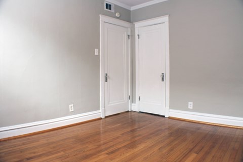 A room with two white doors and wooden floors.