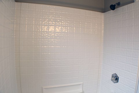 A white tiled shower with a white tub.