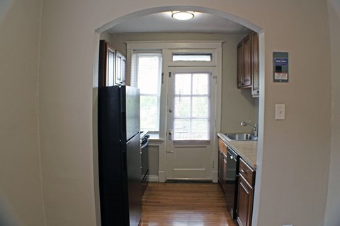 A kitchen with a black refrigerator and wooden floors.
