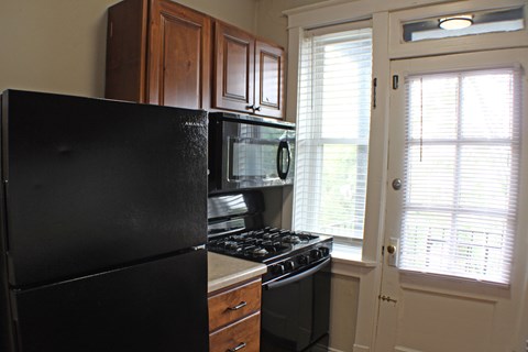 A black refrigerator sits next to a stove in a kitchen.