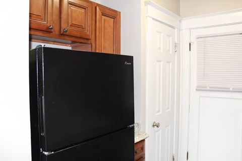 A black fridge in a kitchen with wooden cabinets.
