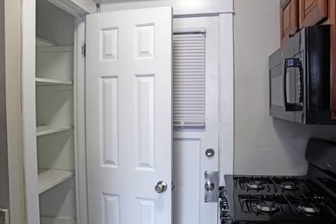 A white door is open to a kitchen with a black stove.
