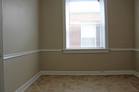A room with a window and tiled flooring.