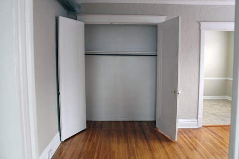 A white door is open to a room with a wooden floor.