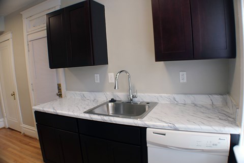 A kitchen with a white counter top and a washing machine.