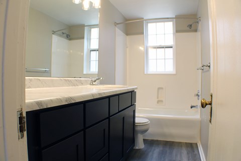 A bathroom with a white counter top and black cabinets.
