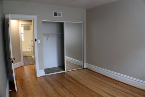 A room with a white closet and wooden floors.