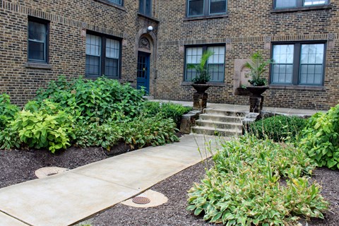 A brick building with a green bush in front.