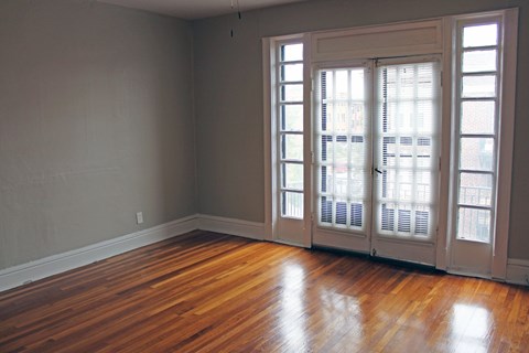A room with a wooden floor and a large window with blinds.