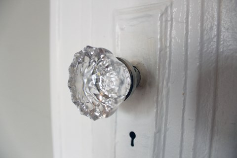 A silver door knob on a white door.