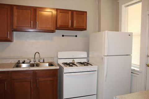A kitchen with a white refrigerator, white stove, and brown cabinets.