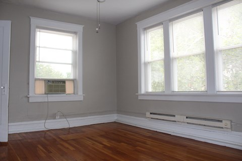 A room with two windows and a wooden floor.