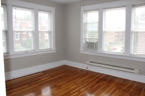 A room with wooden floors and two windows.