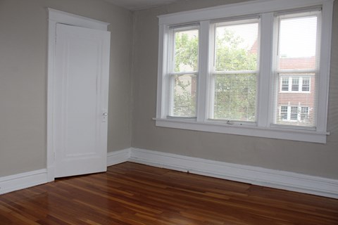 A room with a white door and a window with white blinds.