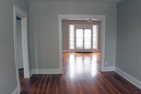 A room with wooden floors and a window with blinds.