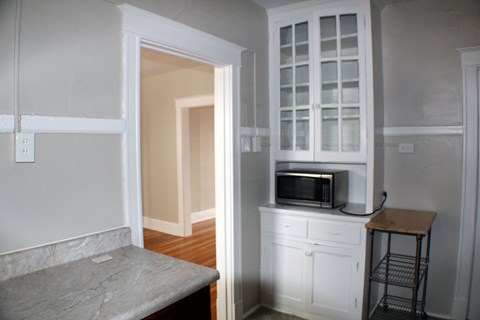 A kitchen with a microwave on top of a cabinet.