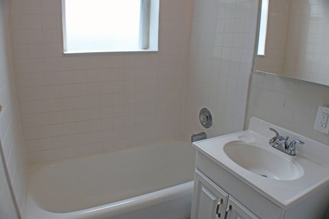A white bathroom with a tub and sink.