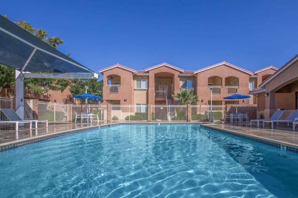 A swimming pool in front of a building with a clear blue sky.