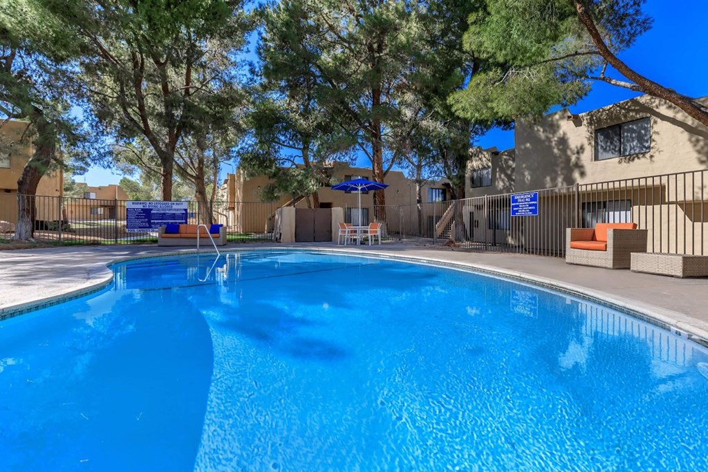 A swimming pool surrounded by trees and a building in the background.