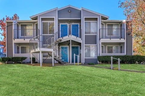 a building with a staircase and a lawn in front of it