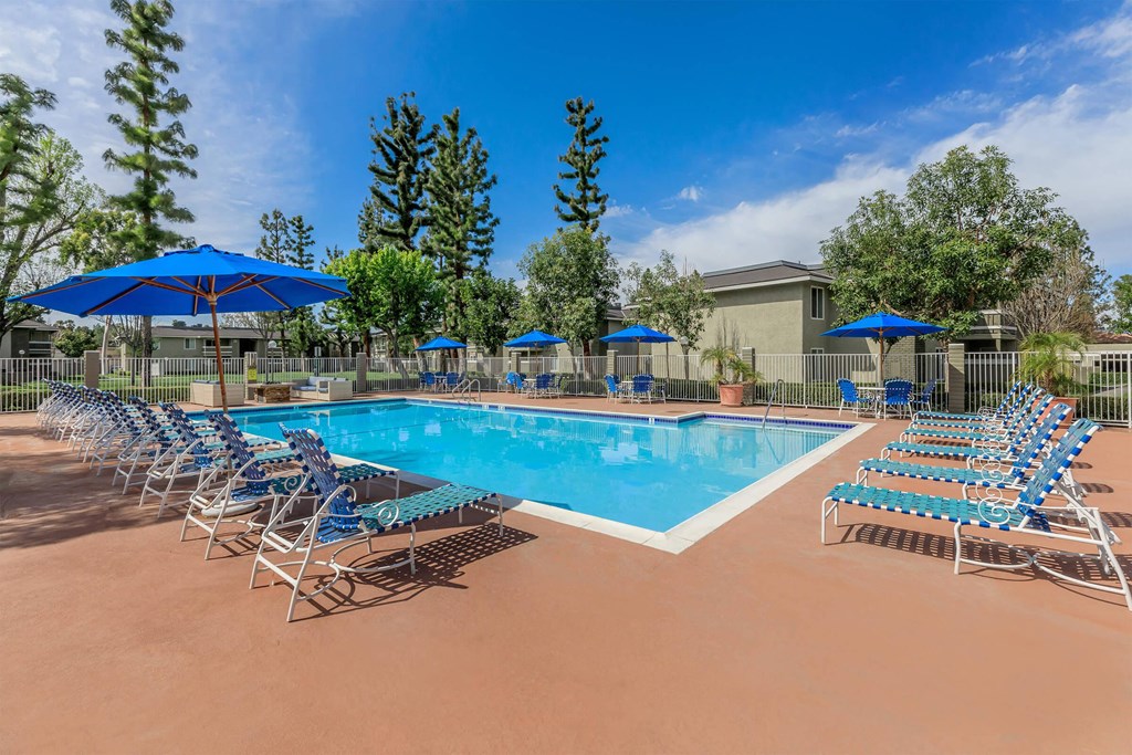 our resort style swimming pool is filled with lounge chairs and umbrellas