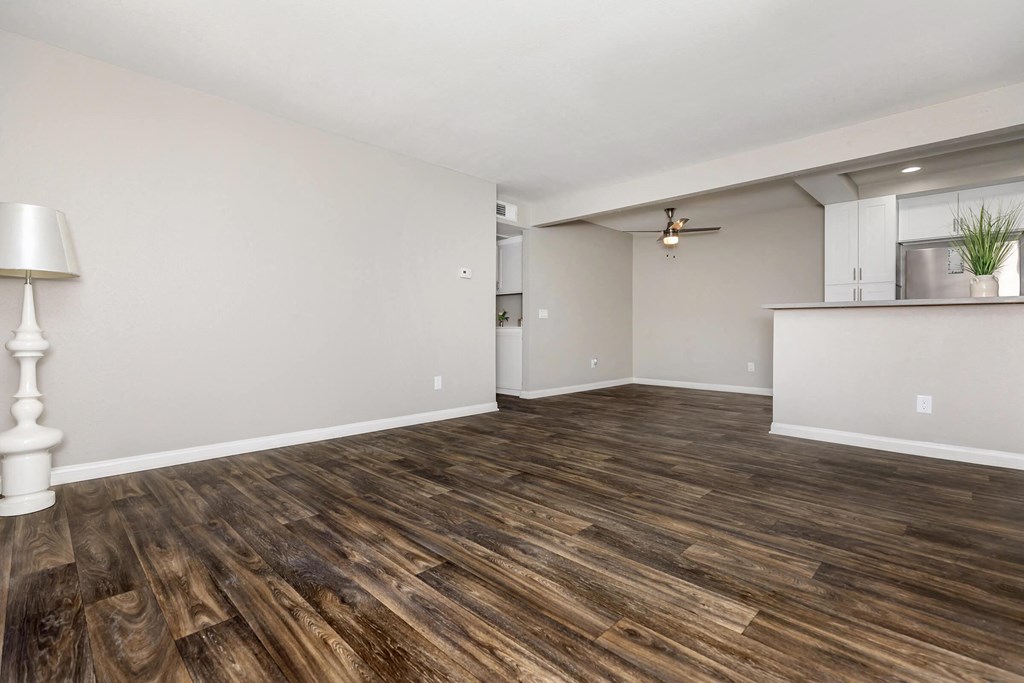 the living room and kitchen of an empty apartment with wood flooring