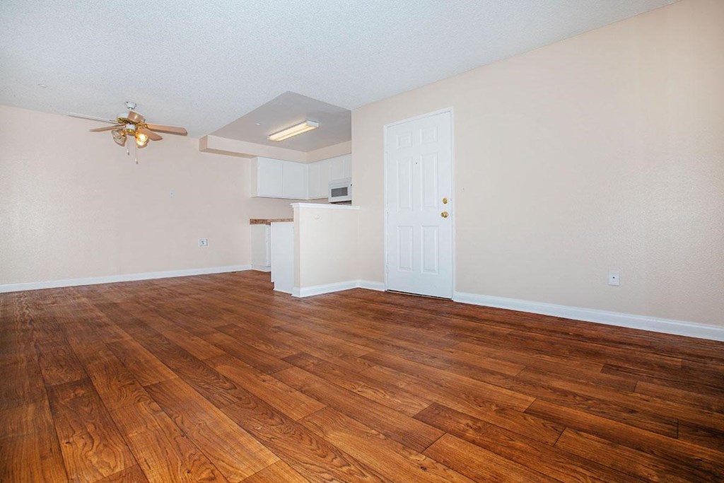 an empty living room with wood floors and a ceiling fan