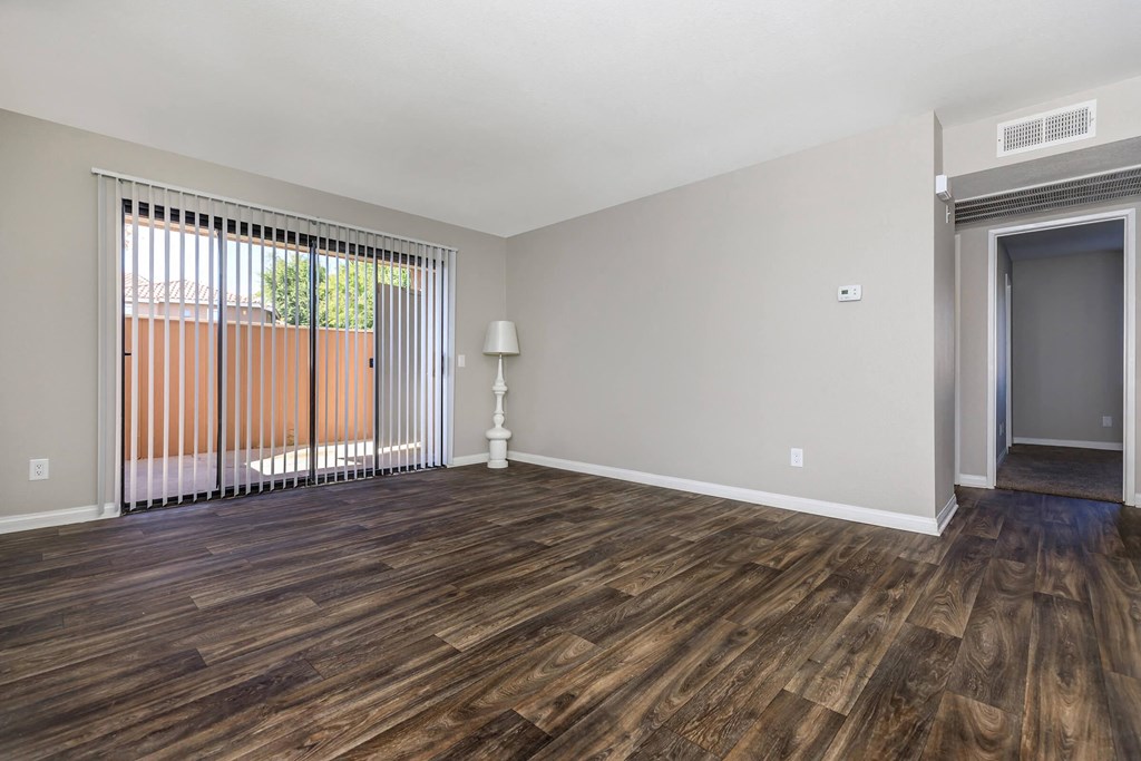 an empty living room with wood flooring and a window