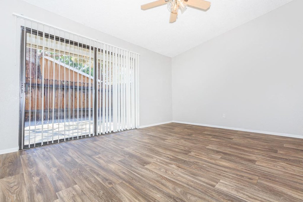 an empty living room with a sliding glass door to a patio
