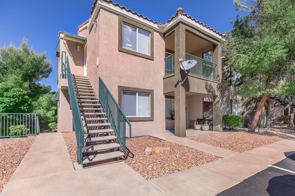the front of an apartment building with stairs and a green staircase