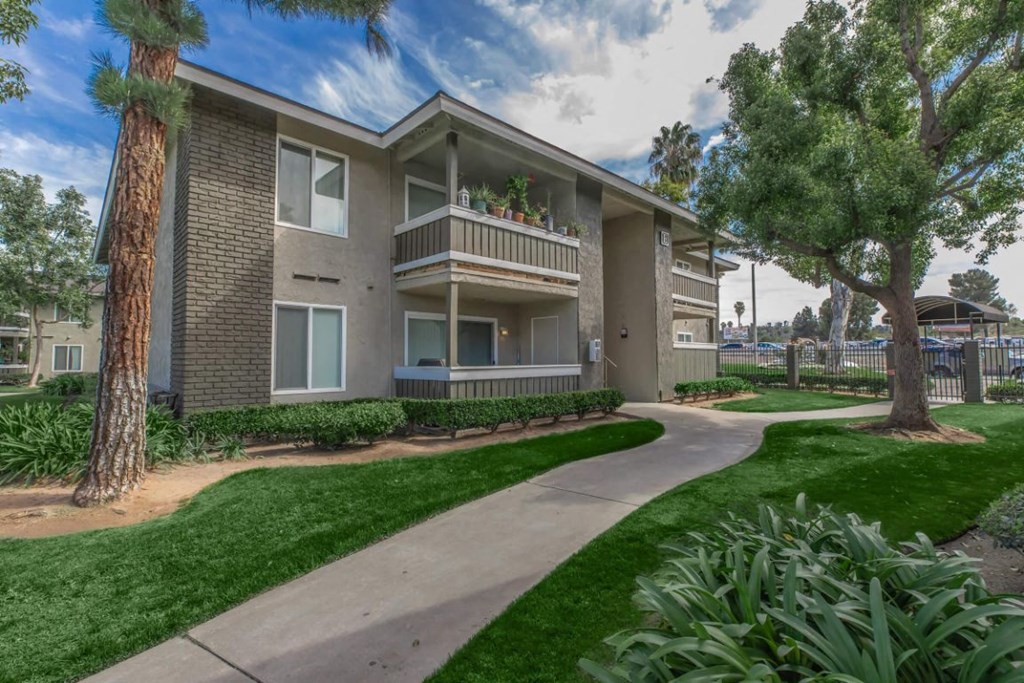 an apartment building with a walkway and grass and trees