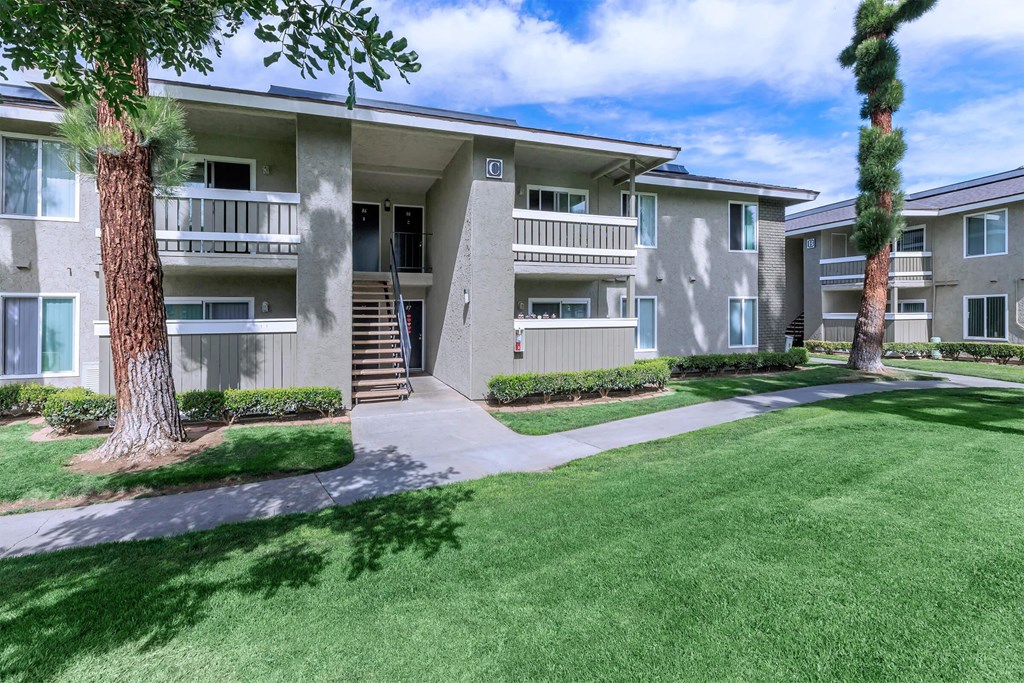 an apartment building with a lawn and trees in front of it