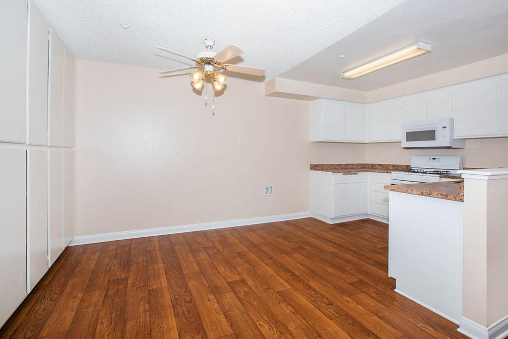 an empty kitchen and living room with a ceiling fan